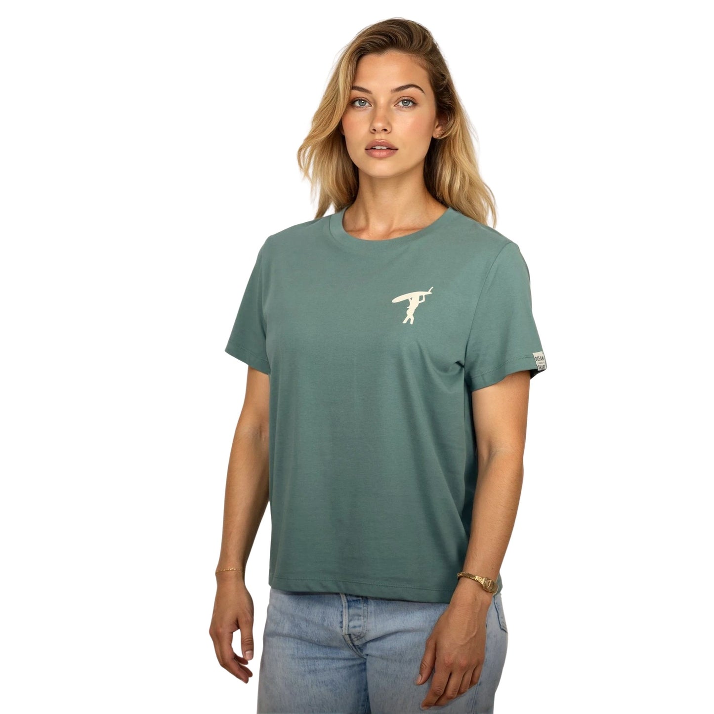 Tee-shirt femme en coton biologique vert sauge avec petit dessin de surfeuse qui marche de dos en écru sur la poitrine, vu de face sur mannequin femme 