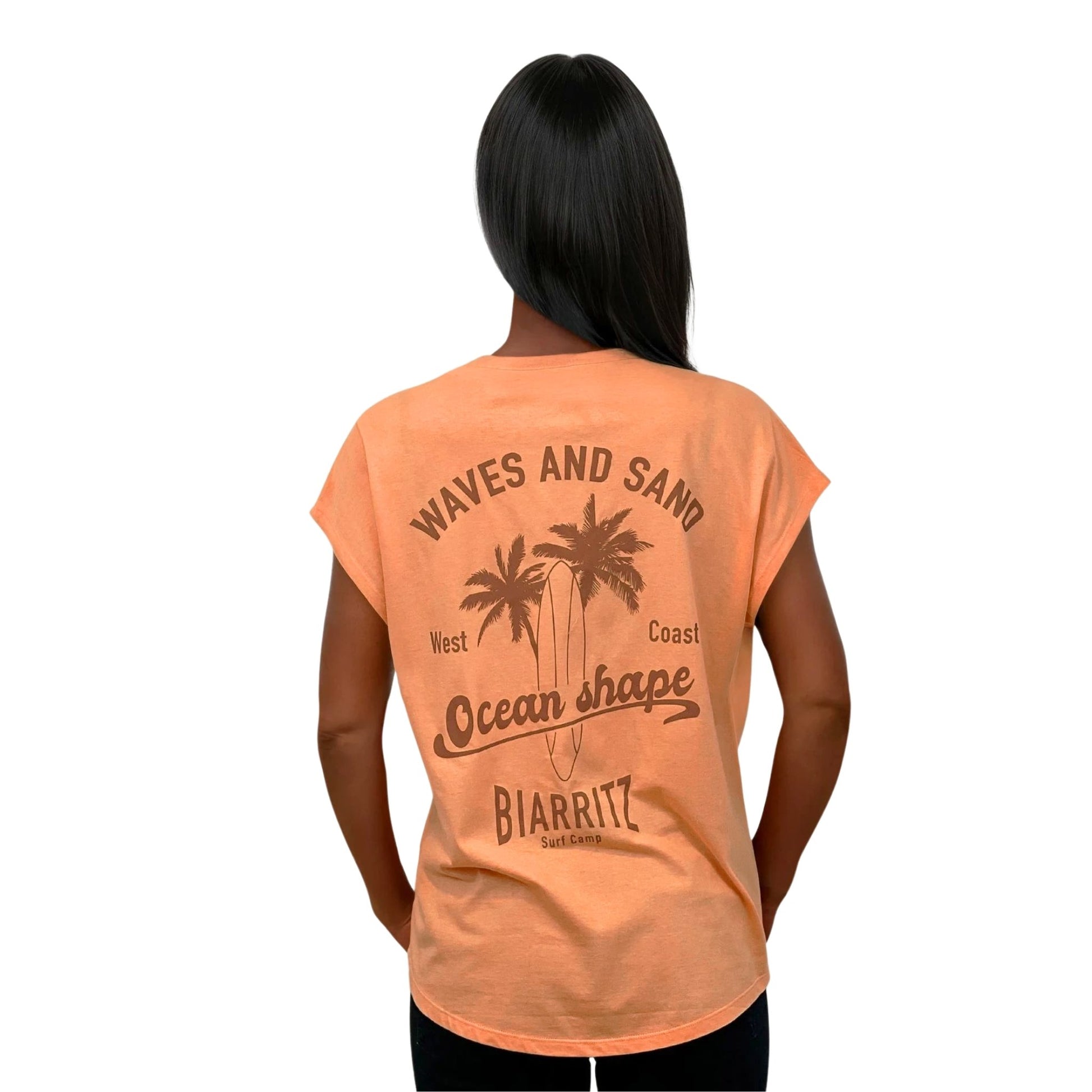 tee-shirt femme en coton biologique couleur abricot. Vu de dos sur mannequin femme.
Dos : grand dessin marron clair de palmiers, planche de surf + écriture "Wave and Sand Ocean Shape Biarritz" dans le dos.