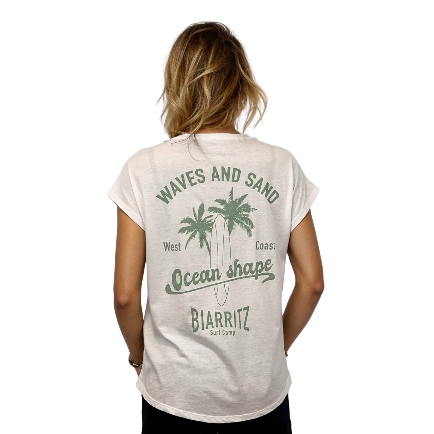T-shirt femme en coton biologique ivoire. Vu de dos sur mannequin femme.
Grand dessin vert pale de palmiers, planche de surf + écritures "Wave and Sand, Ocean Shape Biarritz" dans le dos.
