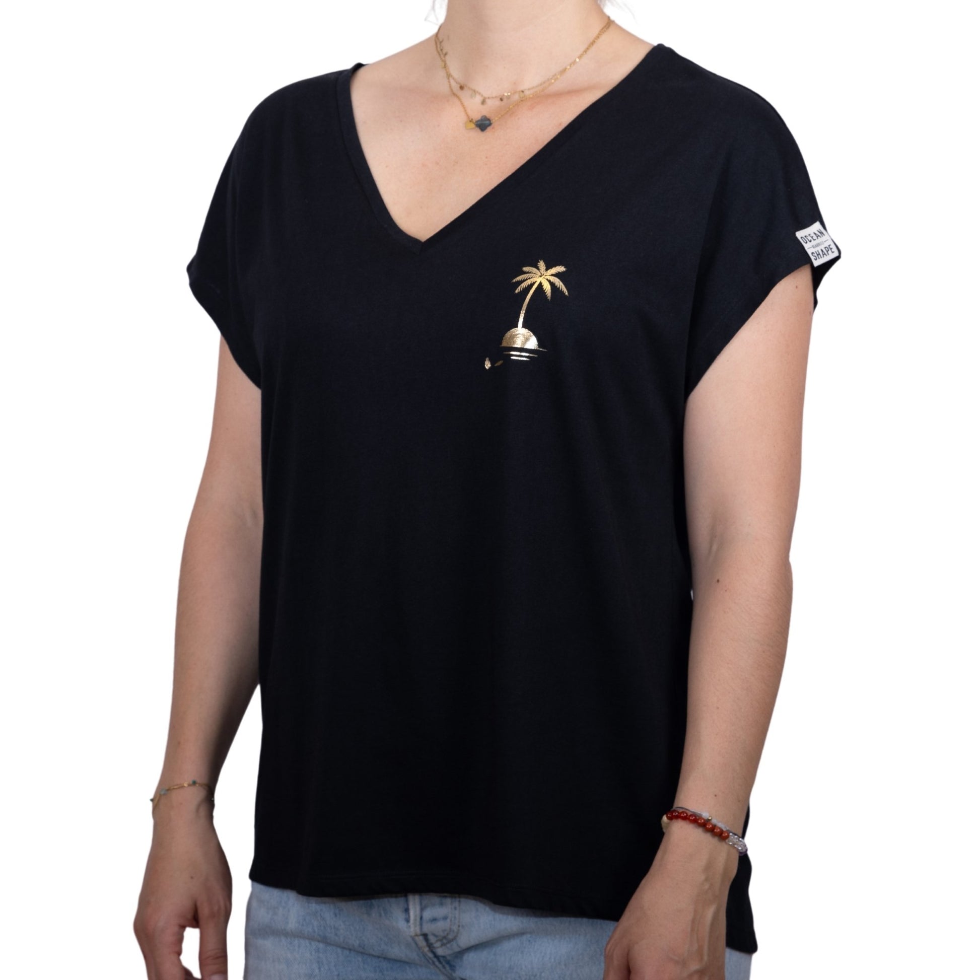Tee-shirt femme en coton biologique noir avec petit dessin palmier sur île couleur doré sur la poitrine, vu de face sur mannequin femme 