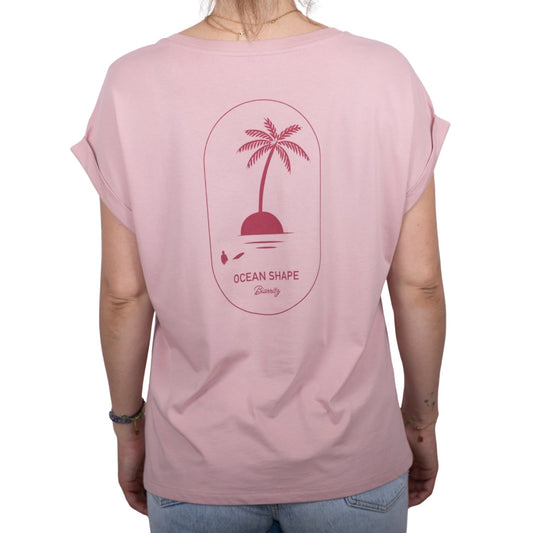 Tee-shirt femme en coton biologique rose pale avec gros dessin palmier sur île et écriture « ocean shape Biarritz » couleur framboise dans le haut du dos, vu de dos sur mannequin femme 