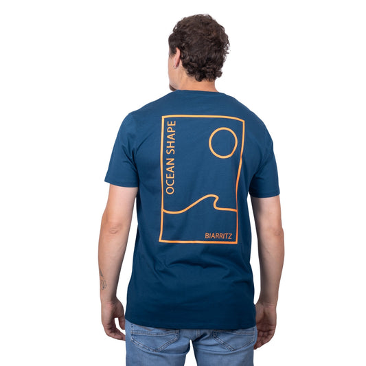 Tee-shirt unisexe bleu petrole en coton biologique avec grand encadré vague / soleil minimaliste + écriture "ocean shape Biarritz" orange fluo dans le dos, vu de dos sur mannequin homme