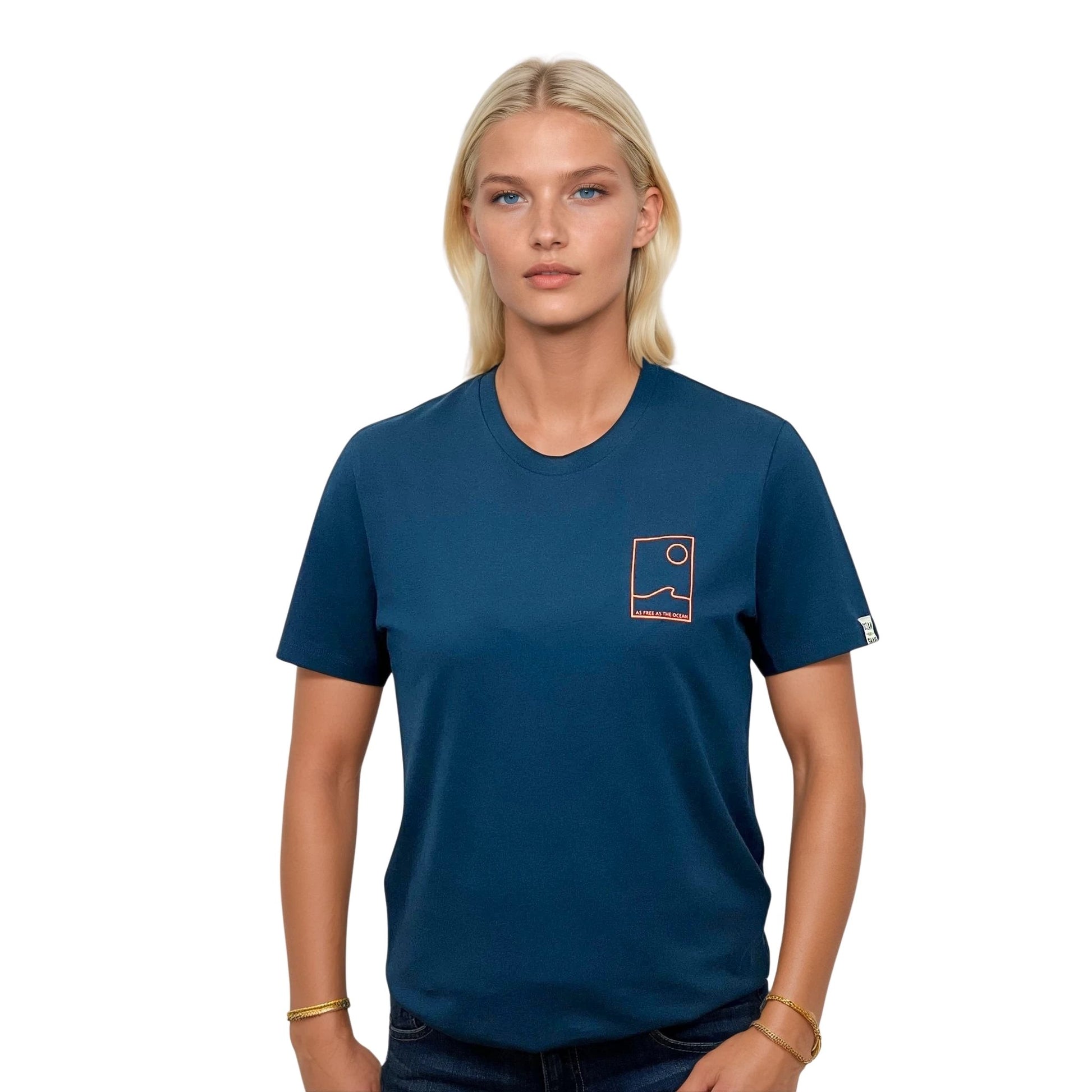 Tee-shirt unisexe bleu petrole en coton biologique avec petit encadré vague / soleil minimaliste + écriture "free as ocean" orange fluo sur la poitrine, vu de face sur mannequin femme.