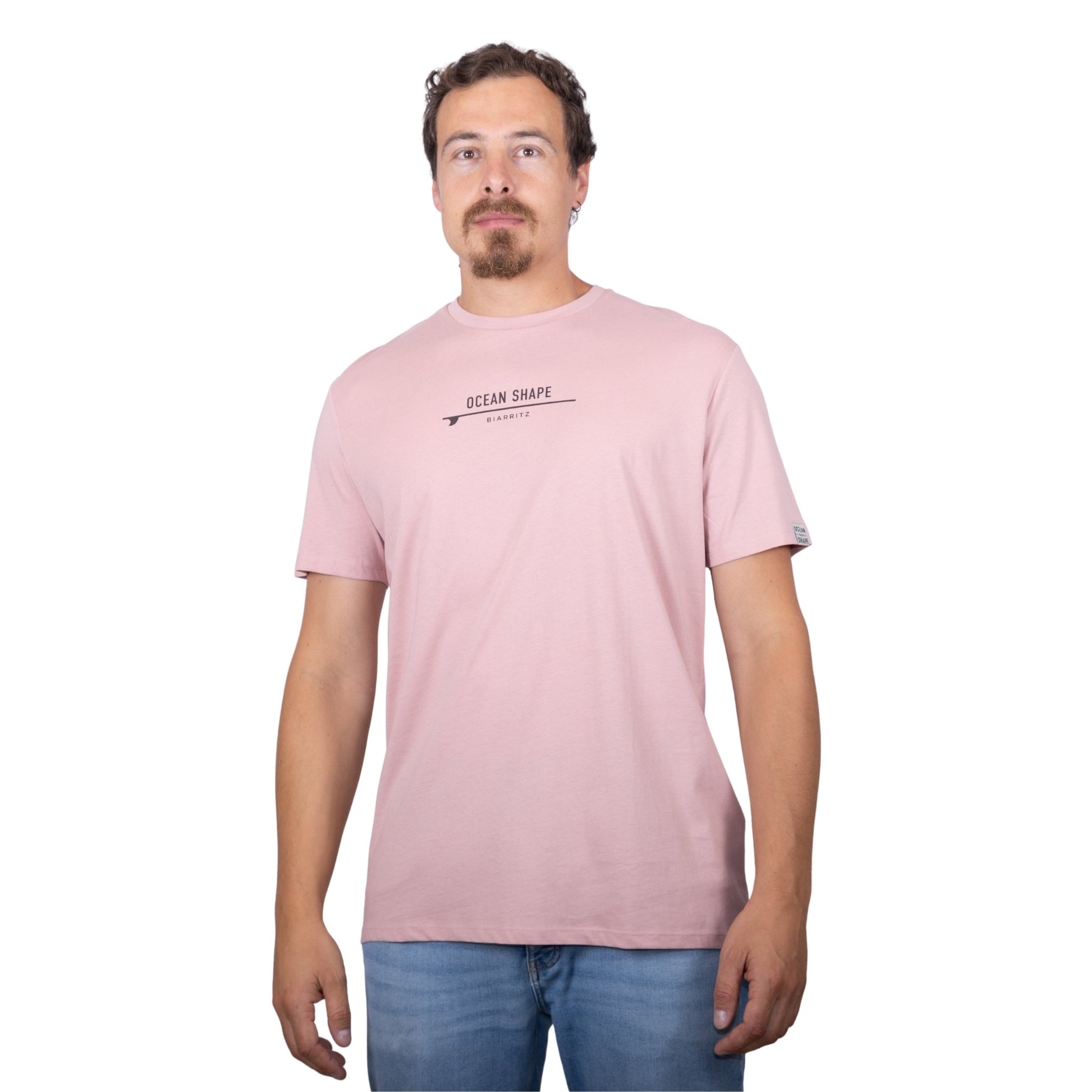 Tee-shirt unisexe rose pale en coton biologique avec petite signature "ocean shape Biarritz" sur surf marron foncé sur la poitrine, vu de face sur mannequin homme
