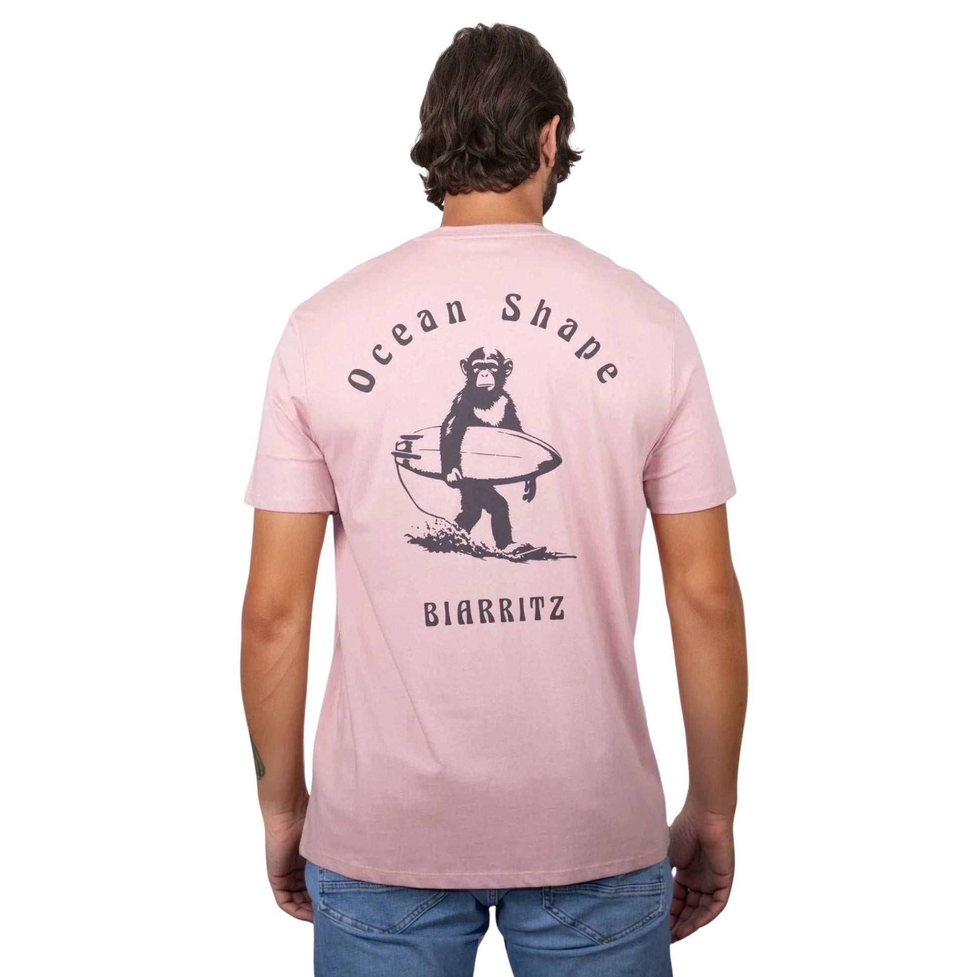 Tee-shirt unisexe rose pale en coton biologique avec gros dessin de singe surfeur et écriture « ocean shape Biarritz » marron foncé dans le dos, vu de dos sur mannequin homme 