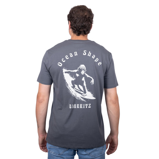 Tee-shirt unisexe gris foncé en coton biologique avec gros dessin de singe qui surfe et écriture « ocean shape Biarritz » beige dans le dos, vu de dos sur mannequin homme 