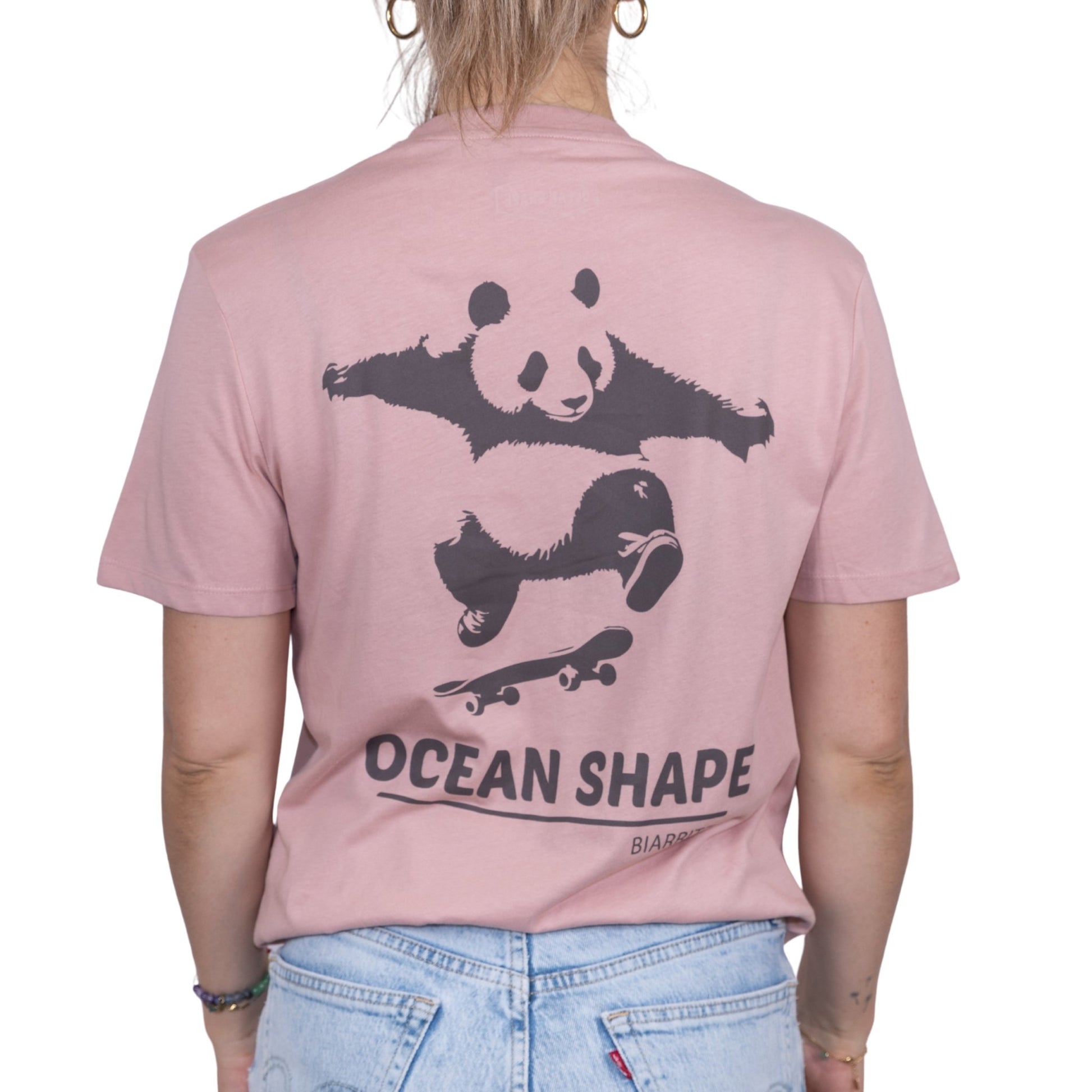 T-shirt unisexe rose pale en coton biologique avec gros dessin de panda skateur et écriture « ocean shape Biarritz » marron foncé dans le dos, vue de dos sur mannequin femme