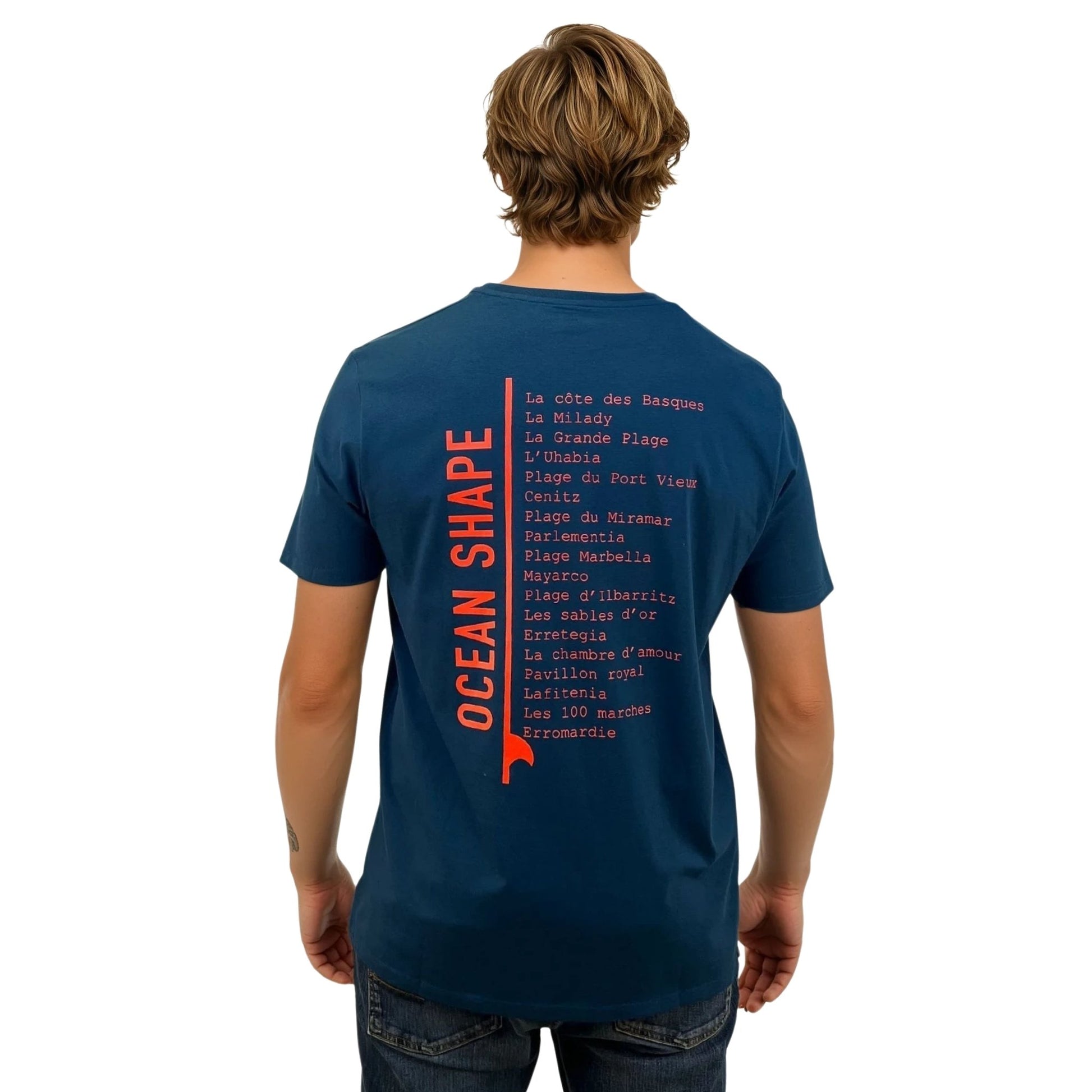 tee-shirt unisexe en coton biologique bleu paon.
Grande liste de plages du pays basque + écriture Ocean Shape orange fluo dans le dos.
Vu de dos sur mannequin homme.