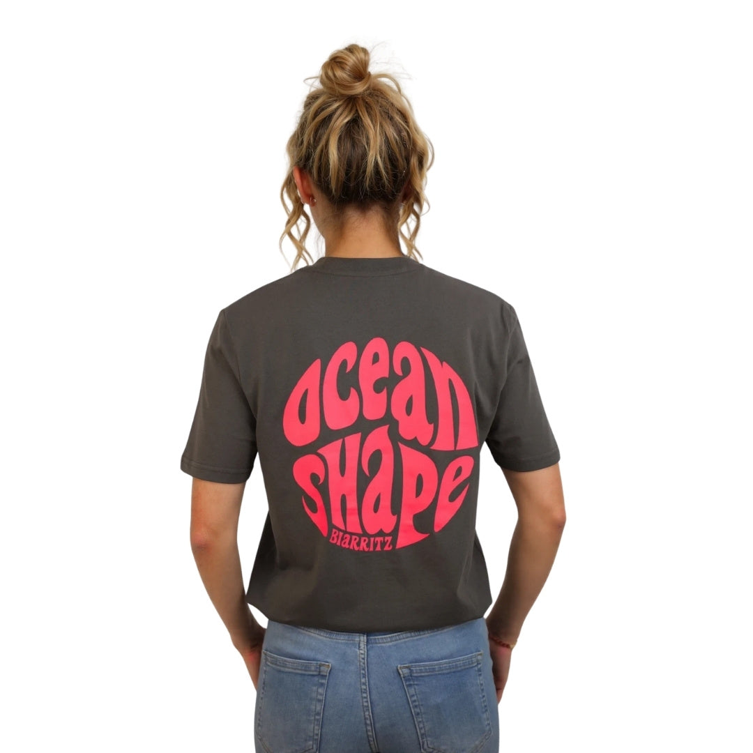 Tee-shirt gris foncé en coton biologique avec grand logo bubble ocean shape Biarritz rose fluo en haut du dos, vu de dos sur mannequin femme.
