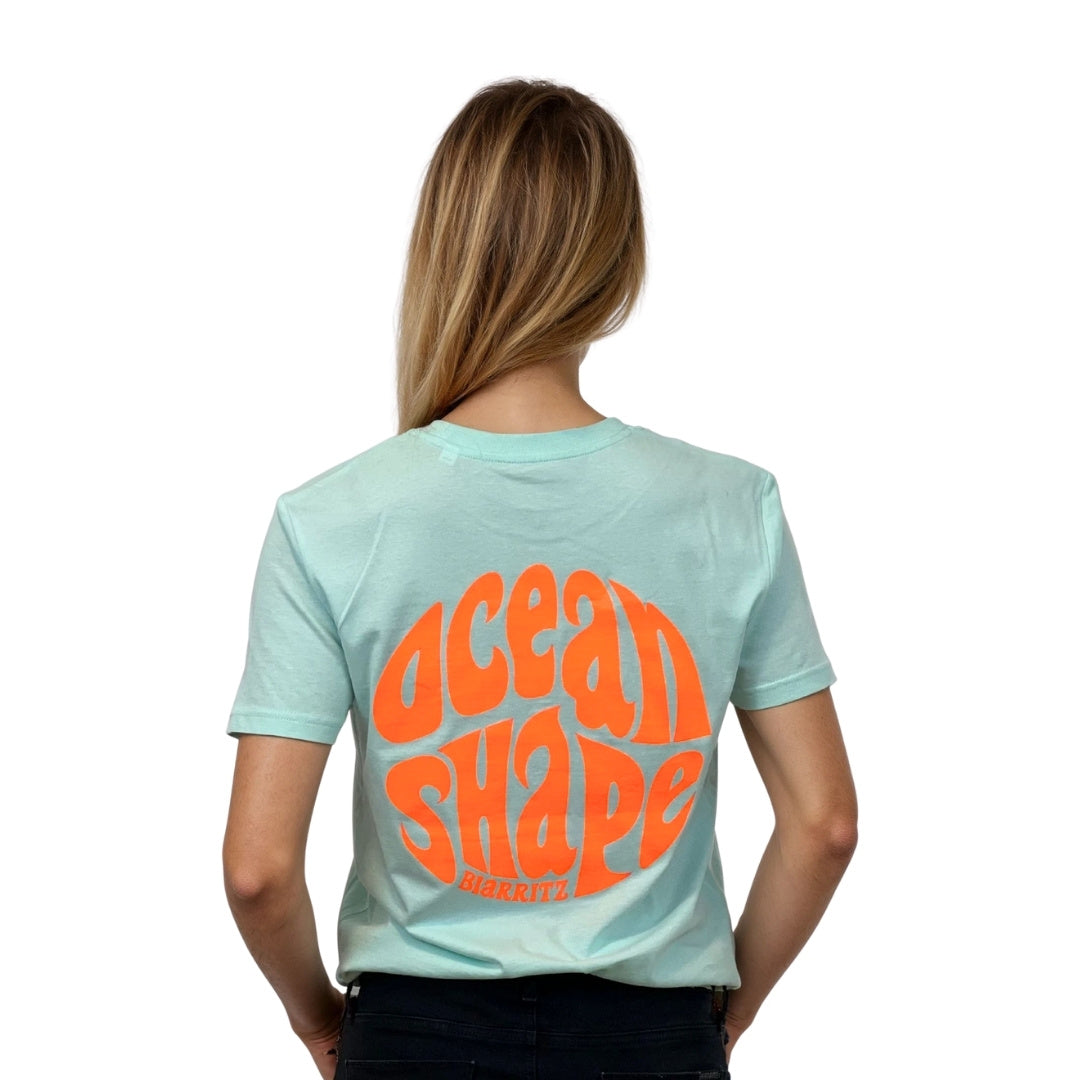 Tee-shirt unisexe en coton biologique bleu caraïbe.
Gros logo bubble "Ocean Shape Biarritz" orange fluo.
Vue de dos sur mannequin femme.