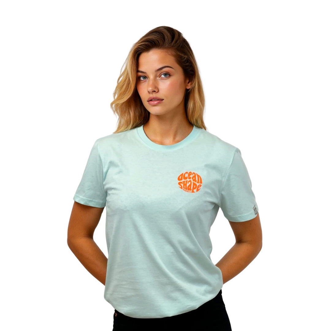 Tee-shirt unisexe en coton biologique bleu caraïbe, petit logo bubble "Ocean Shape Biarritz" orange fluo sur la poitrine gauche.
Vue de face sur mannequin femme.