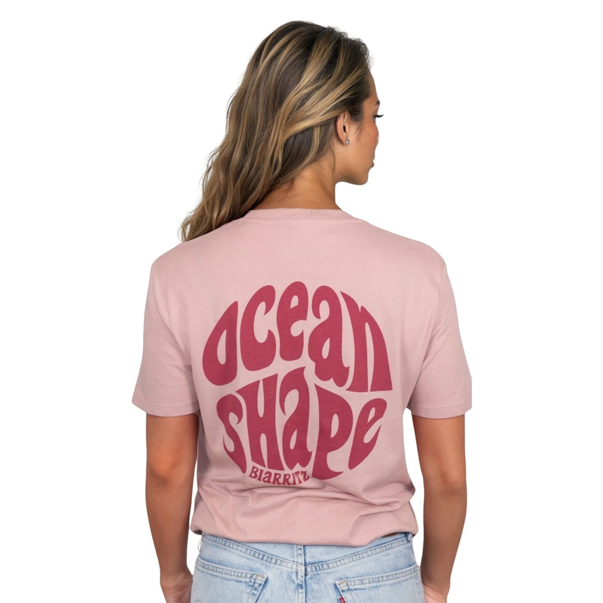 Tee-shirt unisexe rose pale en coton biologique avec gros logo ocean shape Biarritz bubble rose foncé en haut du dos, vu de dos sur mannequin femme