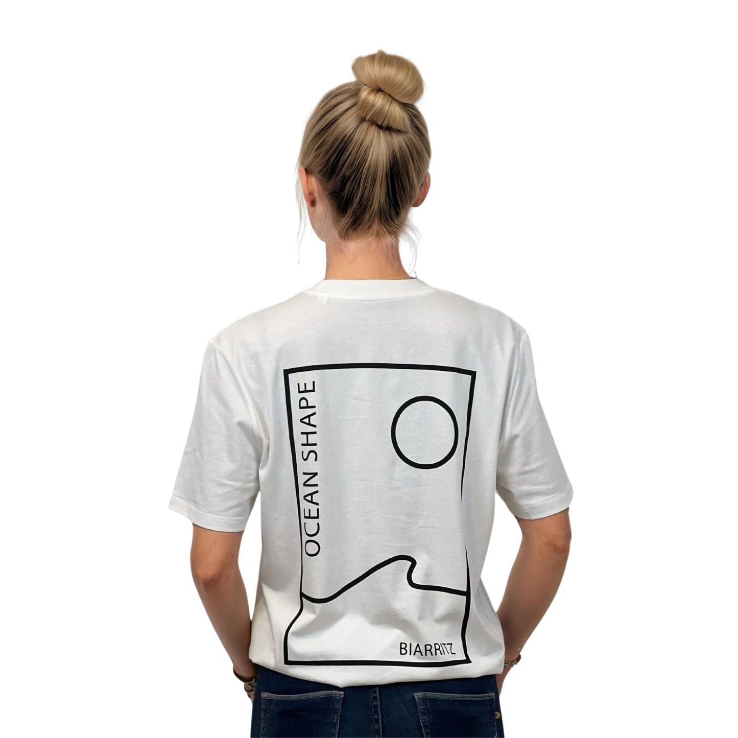 Tee-shirt unisexe blanc en coton biologique avec grand encadré vague / soleil minimaliste + écriture "ocean shape Biarritz" noir dans le dos, vu de dos sur mannequin femme.