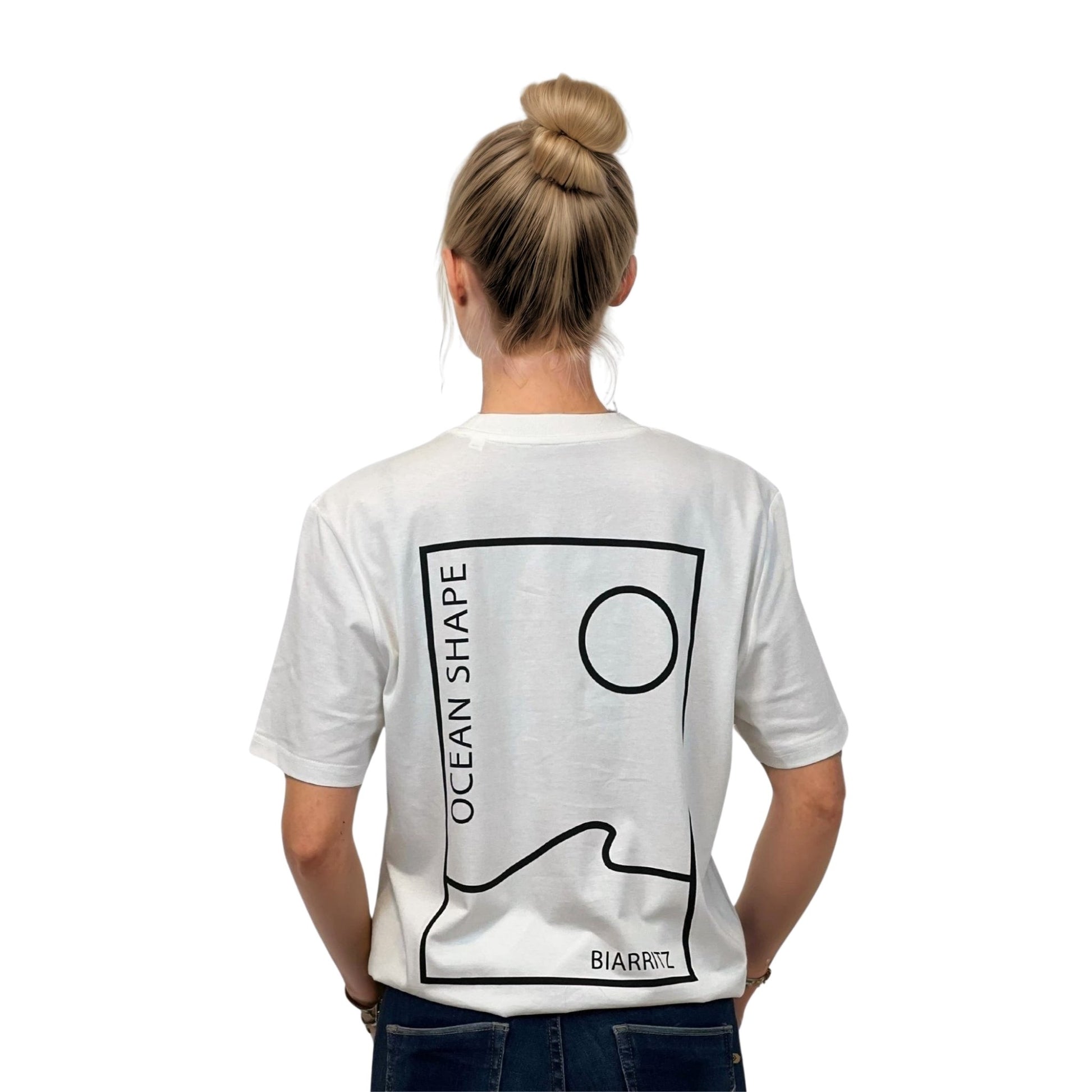 Tee-shirt unisexe blanc en coton biologique avec grand encadré vague / soleil minimaliste + écriture "ocean shape Biarritz" noir dans le dos, vu de dos sur mannequin femme.
