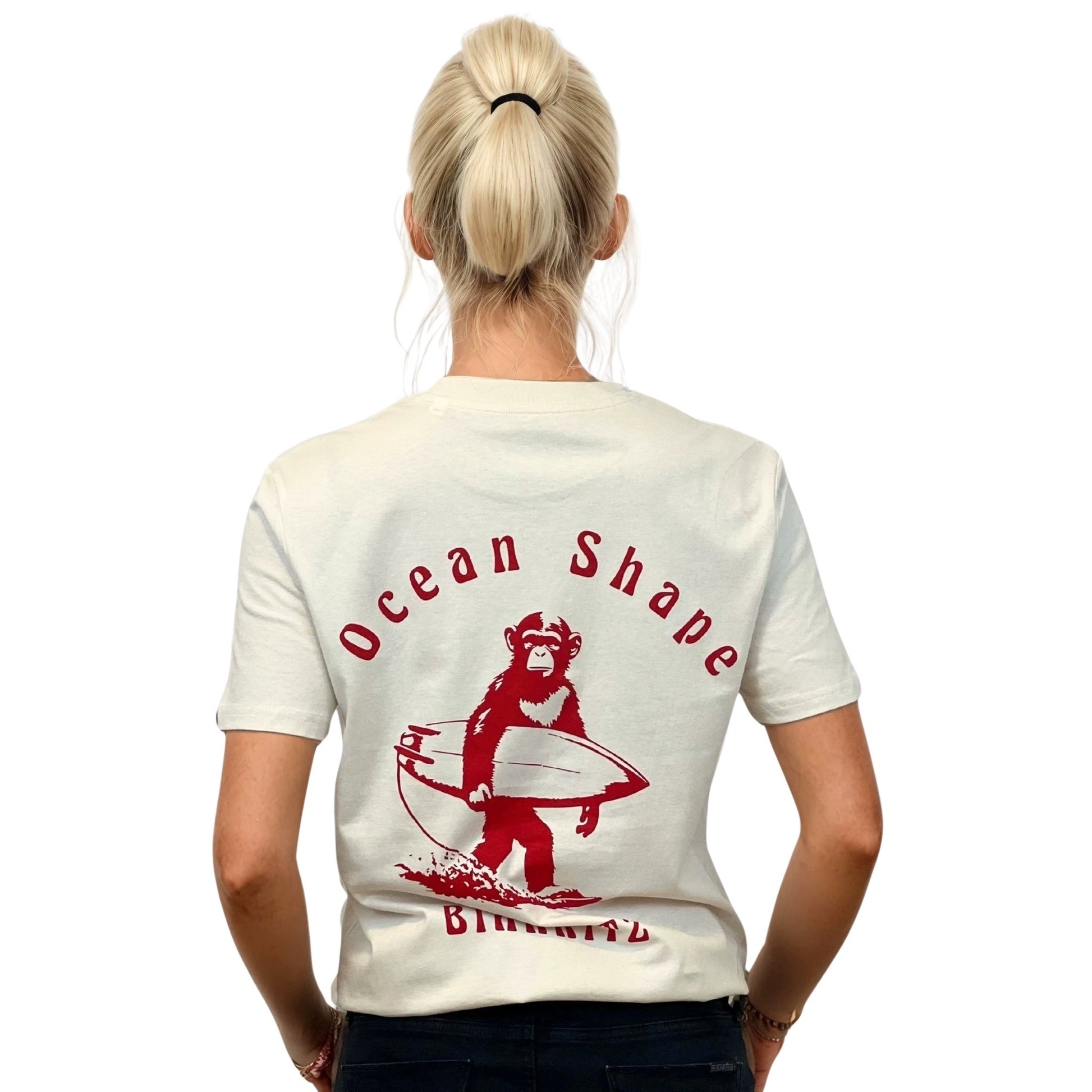 Tee-shirt unisexe écru en coton biologique, grand dessin de singe qui tient une planche de surf + écriture "Ocean Shape Biarritz" dans le dos.
Vu de dos sur mannequin femme.