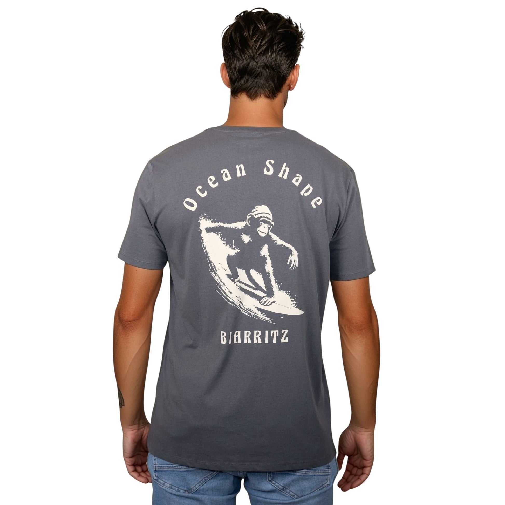 Tee-shirt unisexe gris foncé en coton biologique avec grand dessin de singe qui surfe et écriture « ocean shape Biarritz » beige dans le dos, vu de dos sur mannequin homme.