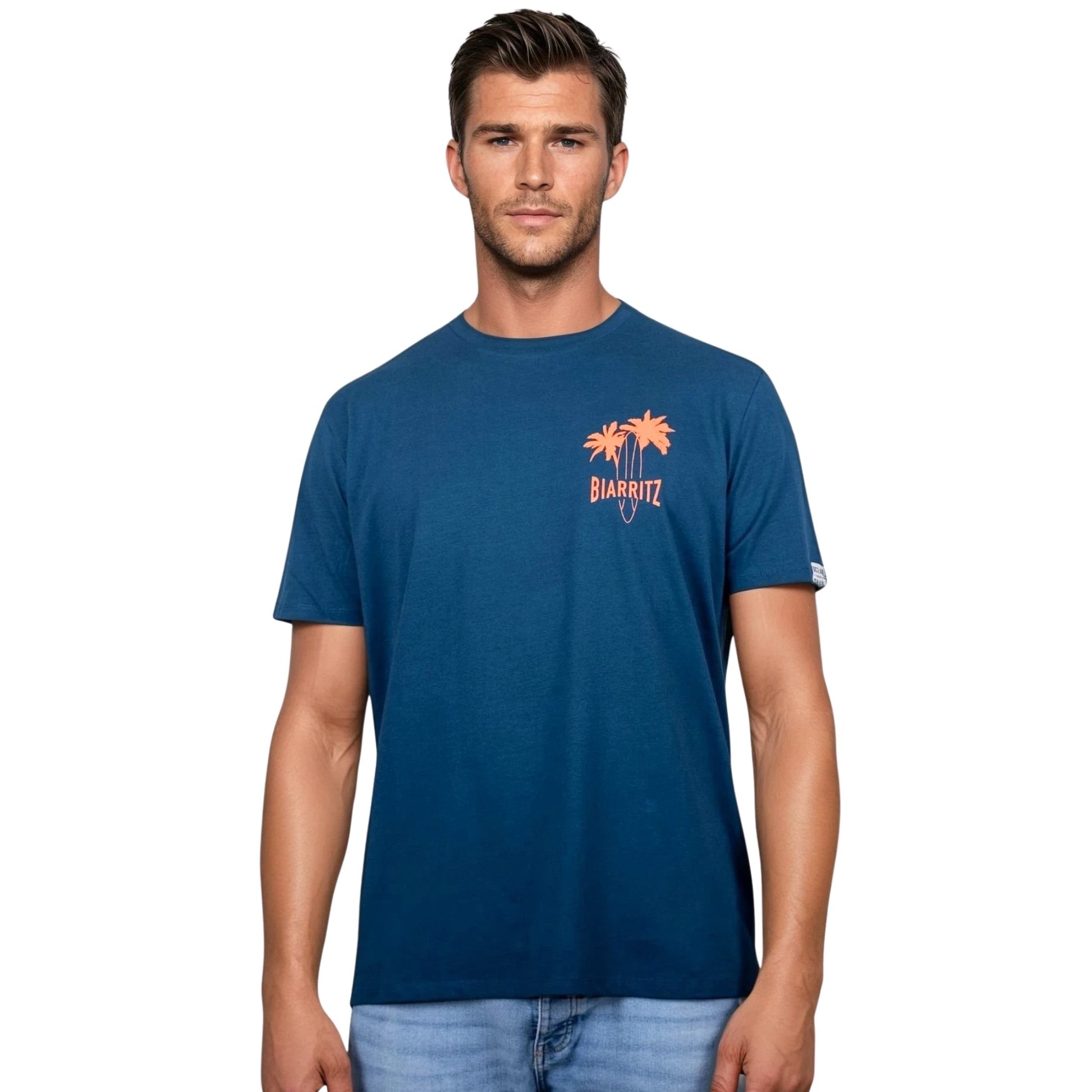 T-shirt unisexe en coton biologique bleu paon avec petit dessin palmiers, planche de surf et écriture « Biarritz » orange fluo sur la poitrine gauche, vu de face sur mannequin homme.