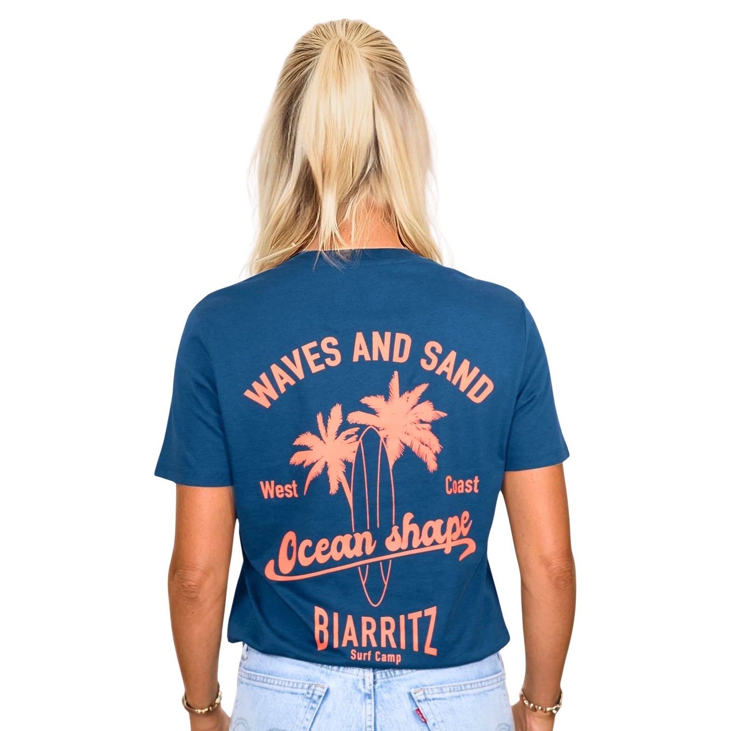 Tee-shirt unisexe en coton biologique bleu paon.
Grand dessin palmiers, planche de surf et écriture « ocean shape Biarritz » et « waves and sun » orange fluo dans le dos.
Vu de dos sur mannequin femme.