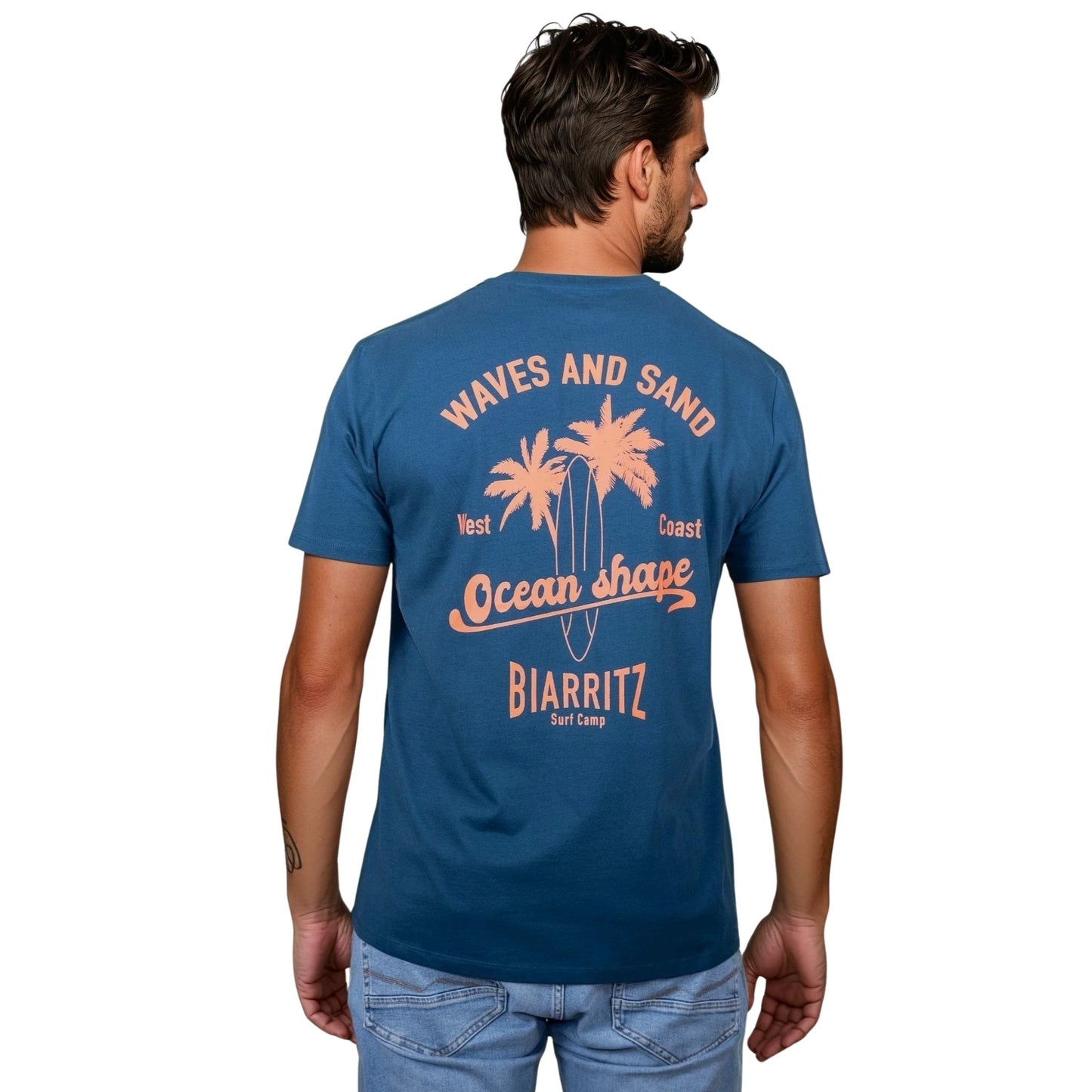 Tee-shirt unisexe en coton biologique bleu paon.
Grand dessin palmiers, planche de surf et écriture « ocean shape Biarritz » et « waves and sun » orange fluo dans le dos.
Vu de dos sur mannequin homme.
